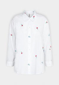 Chemise blanche à manches longues présentant de petites broderies florales rouges et un motif de vélo bleu, col avec boutons sur le devant, coupe décontractée.