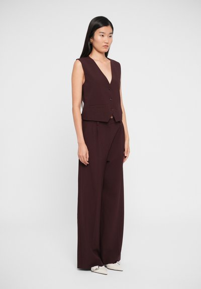 Burgundy sleeveless vest with a V-neck and buttons paired with wide-leg trousers in the same color. Smooth texture; minimalistic design.