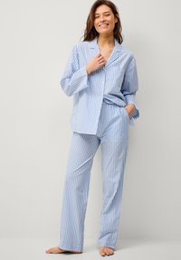 Blauwe en witte gestreepte pyjama-set met een knoopsluiting shirt en bijpassende broek. Van katoen, ontspannen pasvorm en een enkele borstzak.