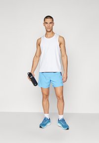 White sleeveless athletic tank top, light blue shorts, black water bottle, and blue running shoes with highlights in black and white accents.