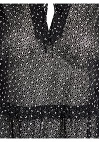 Sort gennemsigtig kjole med et prikket mønster i hvidt og sølv. Detaljer inkluderer en flæset halsudskæring og et lagdelt kant.