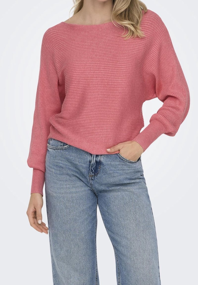 Pull en maille côtelée rose avec un col large et des manches légèrement bouffantes, associé à un jean en denim clair taille haute.