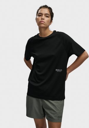 Sort, kortærmet træningsskjorte med et tekstureret mønster og et logo foran. Kombineret med grå shorts med et lignende logo-detalje.