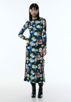 Langärmliges Blumen-Kleid aus dehnbarem schwarzem Stoff, mit einem bunten abstrakten Muster, seitlichen Bändern und einer taillierten Silhouette.