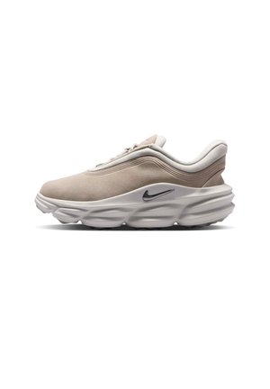 Lichtbeige Nike-sneaker met dikke witte zool en zwart Swoosh-logo, zijaanzicht op witte achtergrond.