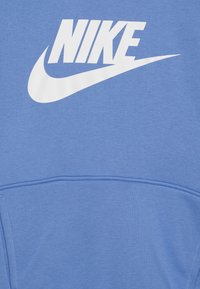 Kék kapucnis pulóver, puha anyagból készült, elöl nagy fehér Nike logóval. Kangourup zsebbel és bordás mandzsettákkal rendelkezik.