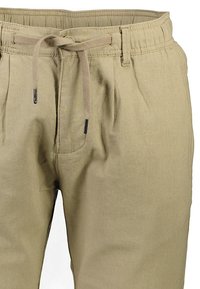 Pantalons beige à cordon de serrage avec une finition texturée, dotés d'une taille élastique, de deux poches avant et de tons neutres et discrets.