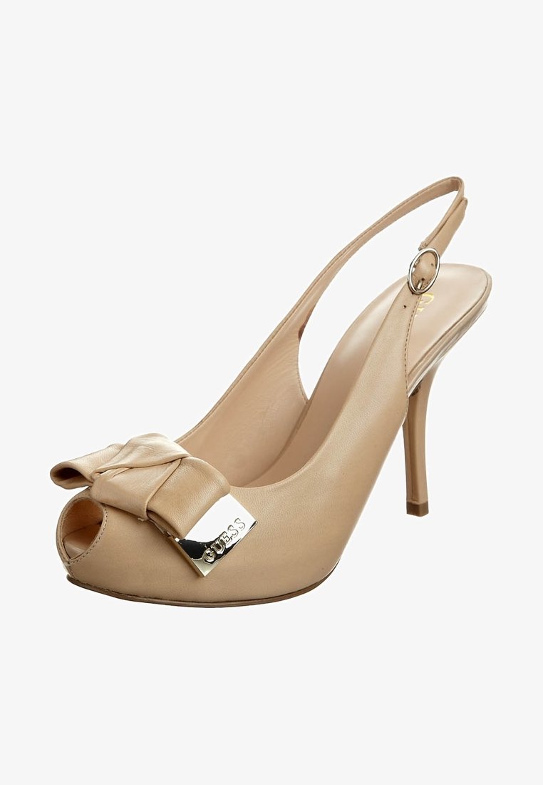 Chaussure slingback beige à talon haut avec bout ouvert, nœud décoratif et plaque métallique du logo Guess sur la bride avant.