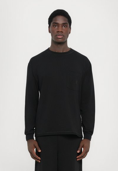 Zwarte long-sleeve shirt van zachte stof met een geribde halslijn en een borstzak met een subtiele logo-detail.