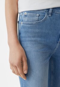 Jasnoniebieskie dżinsy o fasonie slim fit, z pięcioma kieszeniami, małymi metalowymi nitami i delikatnym wyblaknięciem na tkaninie.