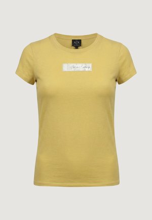 Žluté dámské tričko s krátkým rukávem, přiléhavým střihem a kulatým výstřihem, s stříbrnou obdélníkovou nášivkou s nápisem „Armani Exchange“ na hrudi.