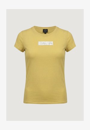 Žluté dámské tričko s krátkým rukávem, přiléhavým střihem a kulatým výstřihem, s stříbrnou obdélníkovou nášivkou s nápisem „Armani Exchange“ na hrudi.