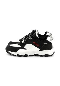 Sneaker chunky in bianco e nero con una combinazione di materiali lisci e testurizzati, dettagli del logo rossi e una suola in gomma testurizzata.