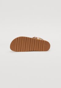 Semelle en caoutchouc marron avec des rainures verticales, présentant un design plat et une surface texturée. Pas d'accents ni de détails supplémentaires visibles.