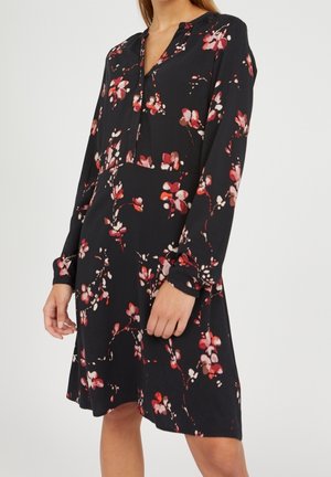 Vestido negro de flores con mangas largas, escote en V y un corte suelto. Los patrones de flores rojas y rosas crean un contraste contra el fondo oscuro.