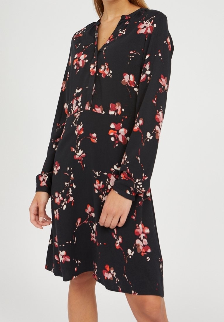 Vestido negro de flores con mangas largas, escote en V y un corte suelto. Los patrones de flores rojas y rosas crean un contraste contra el fondo oscuro.