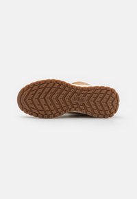 Suela de goma marrón con un patrón de rodadura en zigzag profundo, con el logo de Fila grabado. El material parece duradero y texturizado para un buen agarre.