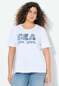 Bílá tričko s krátkým rukávem s grafikou "SEA you soon" a modrými a vzorovanými akcenty. Měkká, lehká látka s volným střihem.