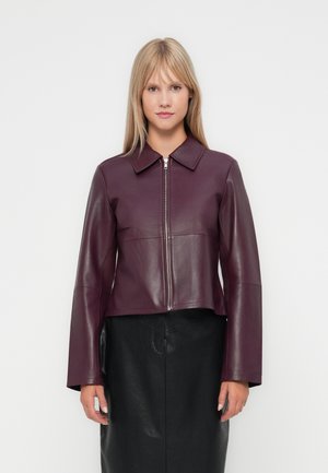 Veste en cuir bordeaux avec un col structuré, fermeture éclair à l'avant et manches longues. Associée à une jupe en cuir noire. Texture lisse.