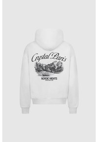 Sweat à capuche blanc avec un motif noir de paysage de montagne, cabane et arbres, textes « "Crystal Paris" » et « "Nordic Nights" » au dos.