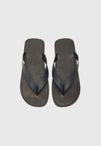Sorte flip-flops med teksturerte stropper, en glatt såle og minimalistisk design. Har en sentral tåpost og subtil merkning på sålen.