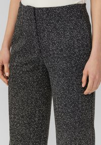 Pantalons noir et blanc à motif pied-de-poule avec une texture douce et une coupe fuselée, dotés d'un devant plat et de poches latérales.