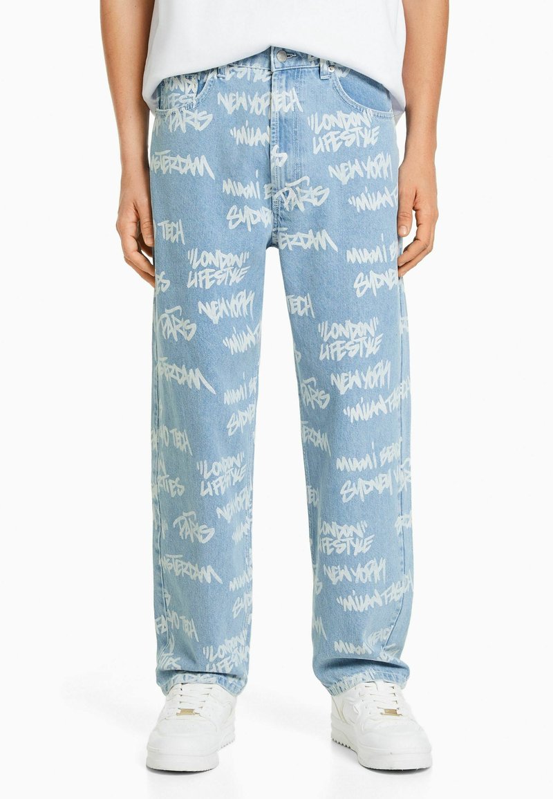 Ljusblå denimbyxor med vita graffitistiltextmönster. Löst skuren med rak ben-design och standard femficksdesign.