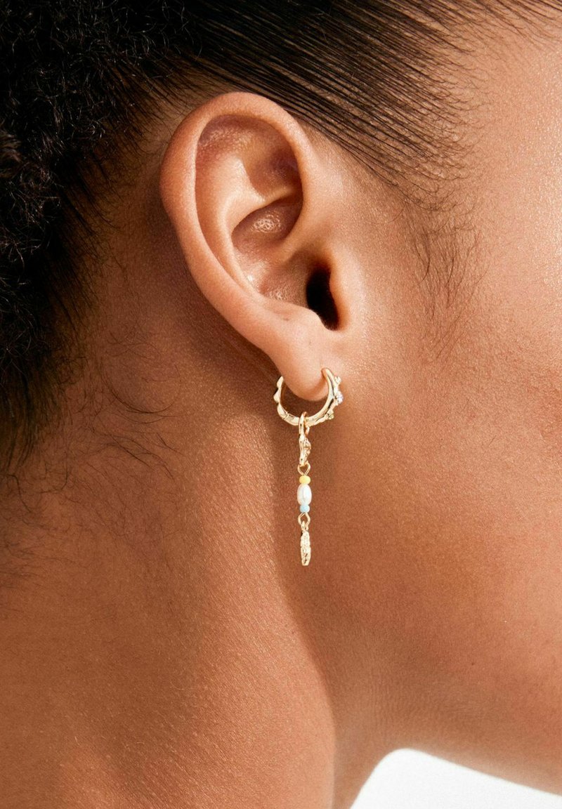 Gold hoop earring with a dangling chain featuring beads in light blue, yellow, and white. Textured design with small crystal accents.