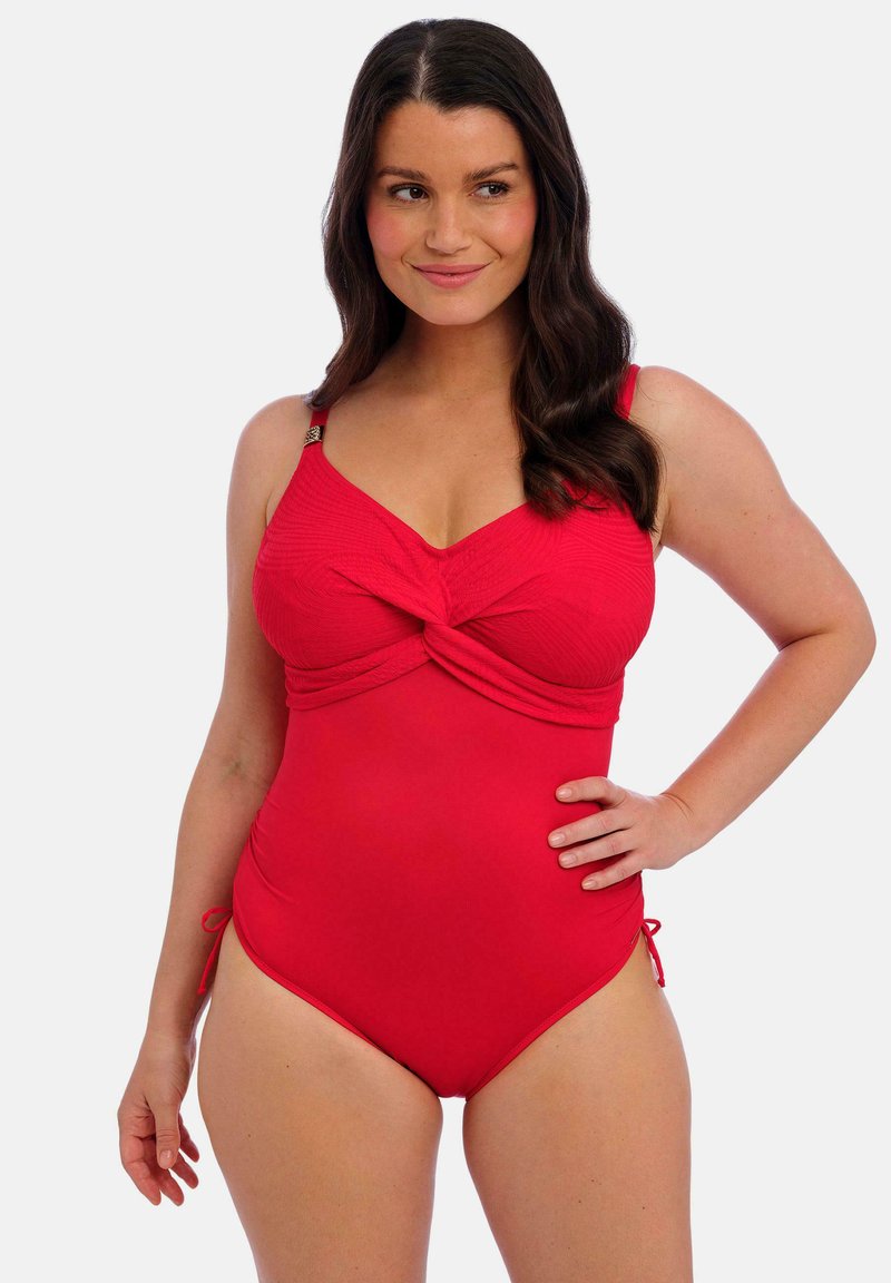 Maillot de bain une pièce rouge avec un design à l'avant twisté, bretelles ajustables et liens sur les côtés. Tissu lisse avec une section supérieure texturée.
