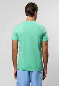 Mündroheline lühikeste varrukatega T-särk pehmest kangast, ümarate kaelustega ja sileda tekstuuriga. Kanda helesiniste lühikeste pükstega.