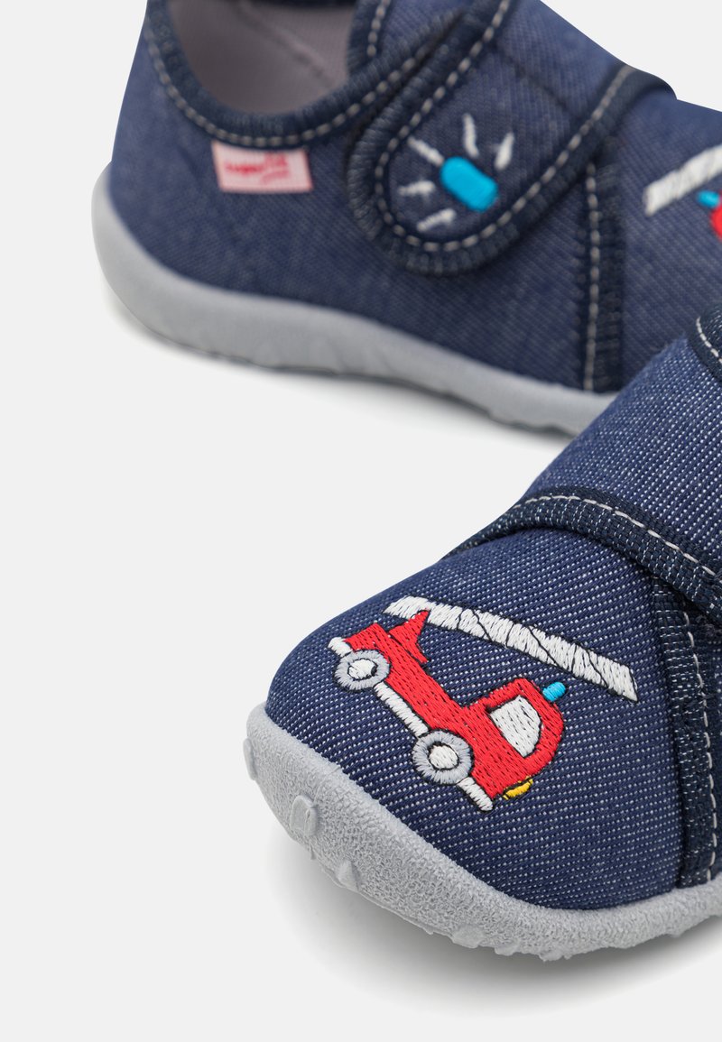 Blaue Denim-Slipper mit grauer Gummisohle, ausgestattet mit einem roten gestickten Feuerwehrwagen- und Lichtdesign. Mit Klettverschluss für ein einfaches Anziehen.