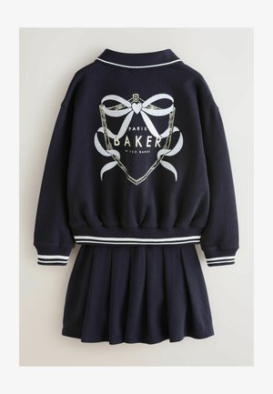 Temno modra obleka z zgornjim delom v stilu bunde in naborki na krilu. Na konicah rokavov in pasu so bele vezenine v obliki pentelj in črt.