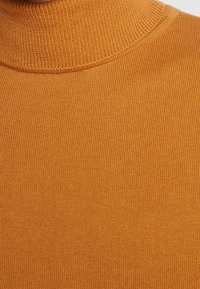 Suéter de cuello alto en un tono mostaza cálido, con una textura acanalada y un diseño ceñido. El material parece suave y elástico.