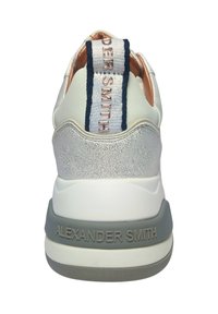 Weiße Sneaker mit strukturierten silbernen Akzenten, einer gepolsterten Ferse und einem auffälligen Logo-Tag in Marineblau und Weiß auf der Rückseite. Gummisohle.