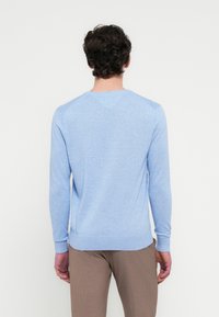 Ανοιχτό μπλε πουλόβερ με μακριά μανίκια, ριμπ μανσέτες και τελείωμα, στρογγυλή λαιμόκοψη και διακριτή υφή. Λείο ύφασμα και λιτός σχεδιασμός.