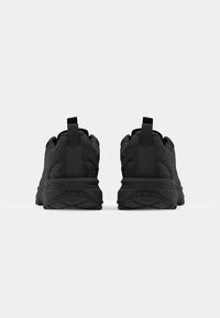 Black athletic shoes with a textured upper, padded collar, and pull tabs. Treaded rubber soles for traction and stability.