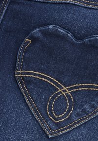 Denimjeans med en hjärtformad bakficka, mörkblå färg, framhävd av gulbrun söm och en slät yta.