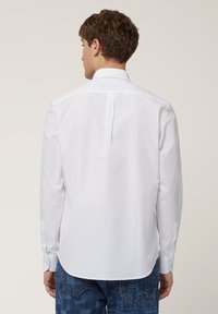 Witte blouse met lange mouwen, een rechte kraag, een rugpas en een ronde onderkant. Voorzien van knoopmanchetten en een gladde, textuurstof.