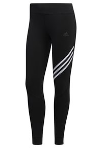 Mustat Adidas-trikoot korkealla vyötäröllä, joissa on kolme valkoista vinoraitaa oikealla reisillä ja hillitty Adidas-logo raitojen yläpuolella.