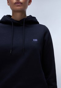 Marineblauwe hoodie met een trekkoordkap en een klein paars logo op de borst. Gemaakt van een zachte, gestructureerde katoenmix.