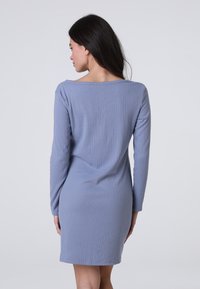 Abito a maniche lunghe a coste di colore azzurro chiaro con scollatura a barca, forma aderente e lunghezza fino al ginocchio. Texture morbida, dettagli di design minimi.