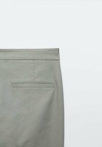 Pantalon gris en tissu lisse, coupe droite et une poche arrière avec un contour de couture subtil.