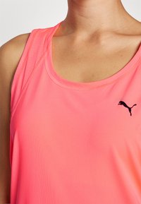 Svetlo roza brezrokavnik za šport, izdelan iz gladkega blaga, z zaobljenim ovratnikom in majhnim črnim logotipom Puma spredaj.