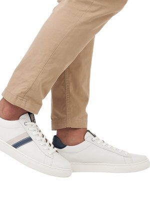 Weiße Sneakers mit marineblauen Akzenten und seitlichen Streifen, Lederoberteil, flache Sohle und Schnürdesign, kombiniert mit beigen schmal zulaufenden Hosen.