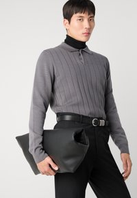 Hallikka halline suvepolo särk, millel on hall ribadega ja kaelus, must turtleneck-särk all, must vööd ja pehme must nahast kott.