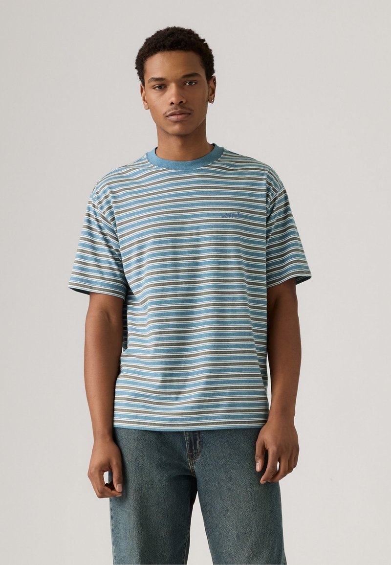 Striped short-sleeve t-shirt in blue, beige, and white; features a round neck and relaxed fit. Material appears soft with a casual design.