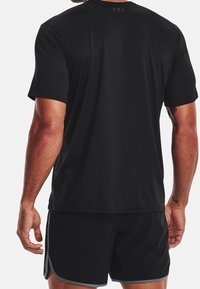 Svart atletisk t-shirt med korta ärmar, tillverkad av mjukt och lätt material. Inkluderar rund hals och en Under Armour-logotyp på baksidan.