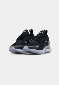 Ett par svarta Nike Air Max 270-sneakers med vita sulor, meshtoppar och synligt luftdämpning i hälen, visade från en fram-vänster vinkel.
