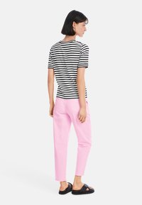 Striped black and white t-shirt, pink tailored pants, black sandals. Short sleeves, relaxed fit, visible stitching on pants.