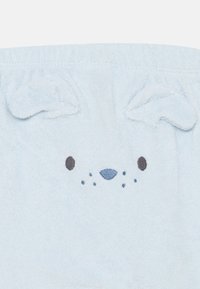 Helles blaues, flauschiges Material mit einem gestickten Tiergesicht mit Ohren, dunklen Emailleaugen und einer weichen Nase. Einfaches Design mit subtilen Details.